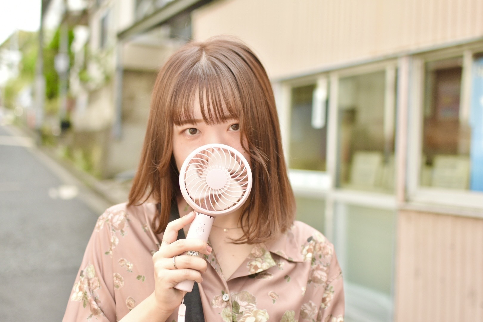 商店街でハンディファンを手に微笑む女性のポートレート撮影